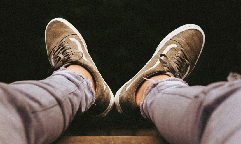 a person wearing gray pants and green sneakers