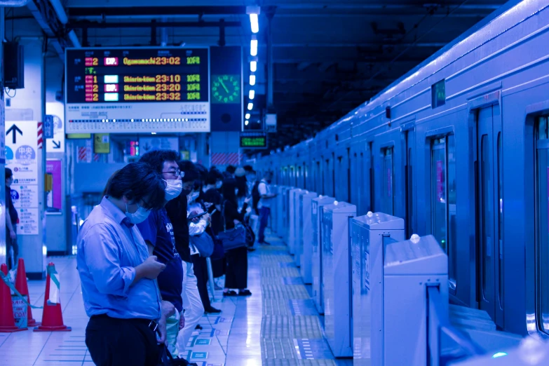 two people wearing masks stand next to the rails on a train