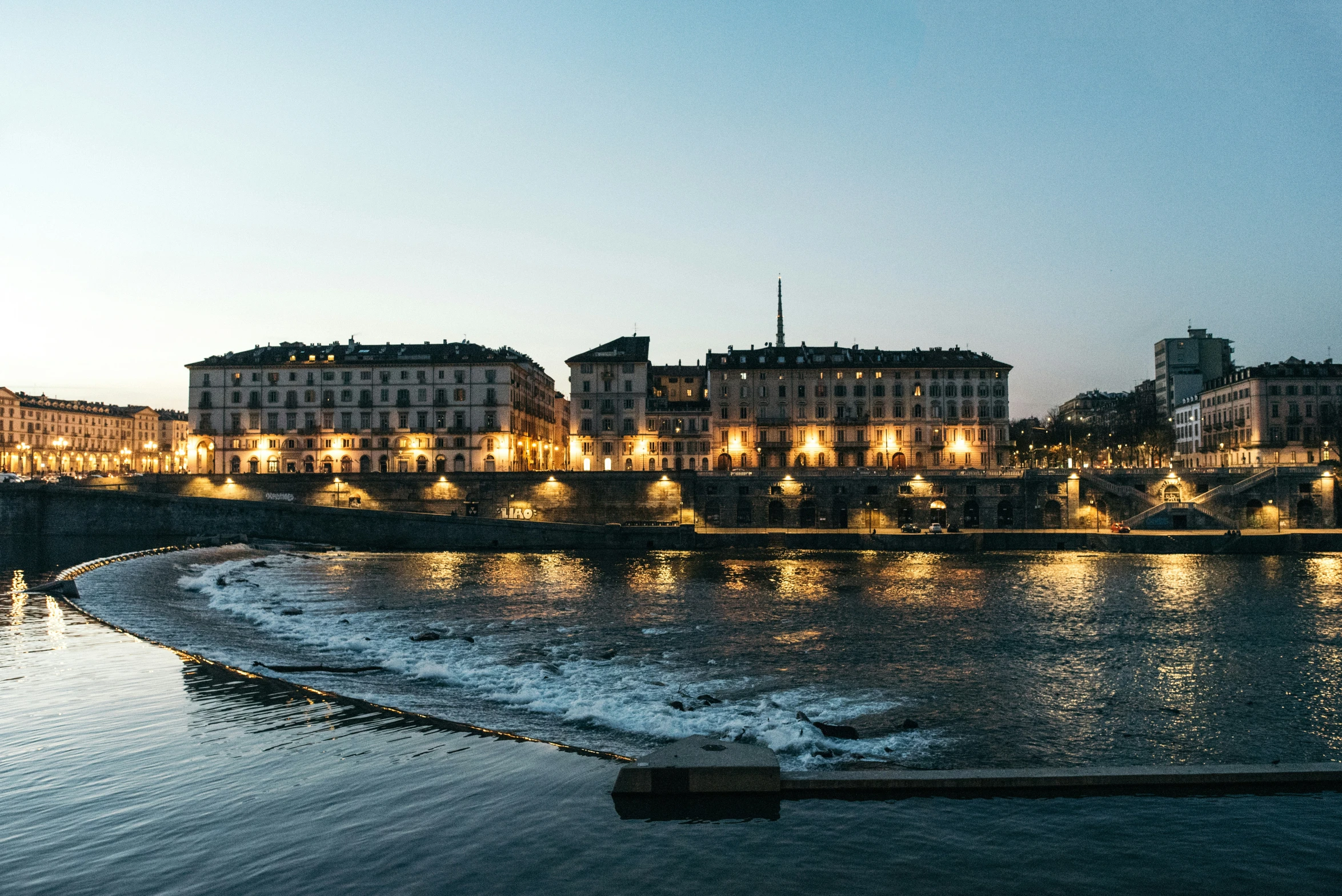 a large body of water with some lights on the shore