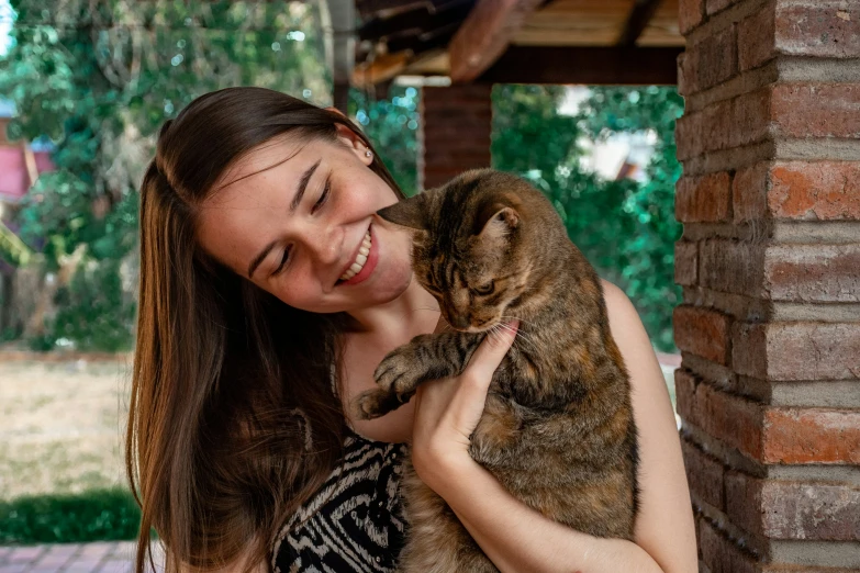 a woman smiling and holding a brown cat