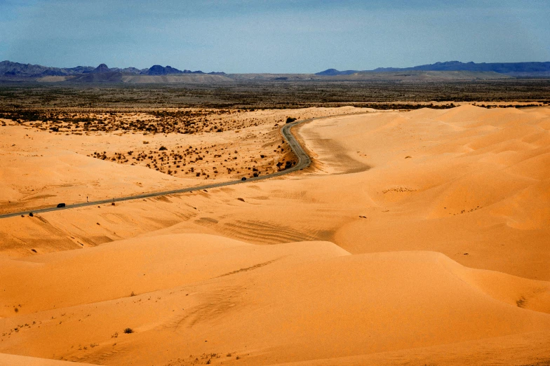 there is a road going through sand in the desert