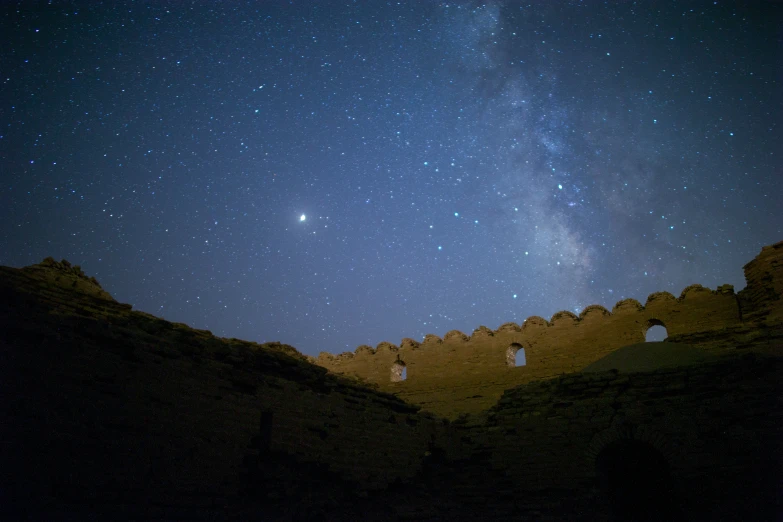 stars are lit up in the night sky above an old castle