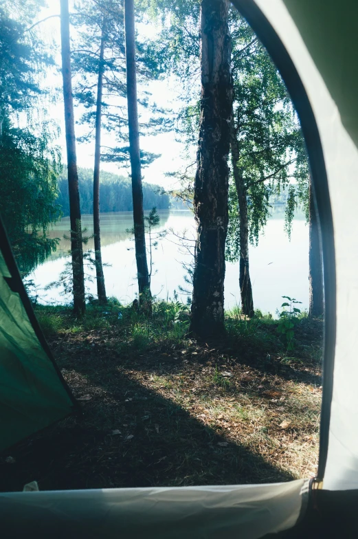 a tent near a pond, near some trees