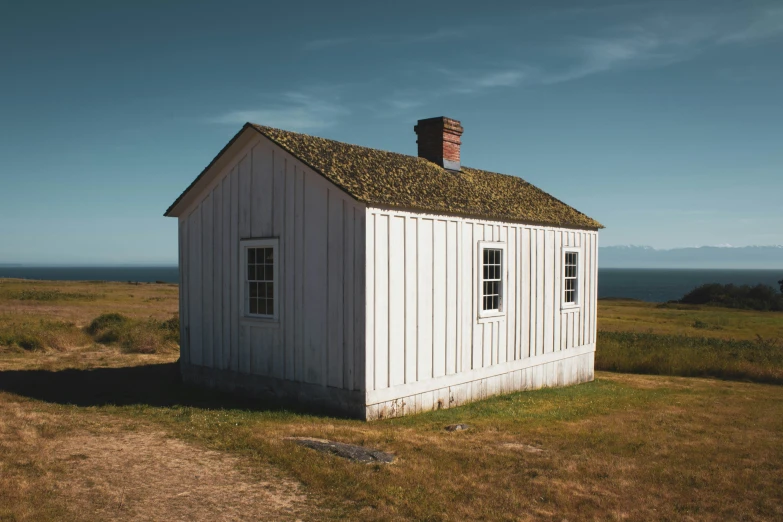 a white building with a chimney next to an open field