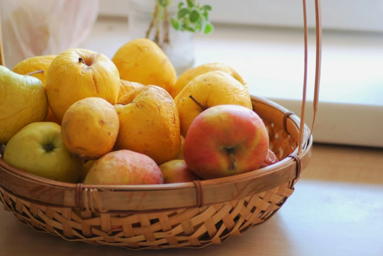 a basket filled with some yellow and red apples