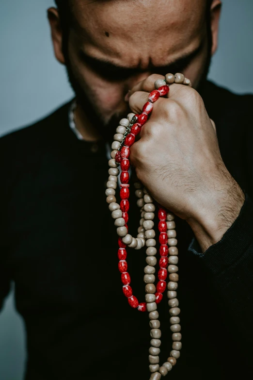 a man wearing beads and a black sweater