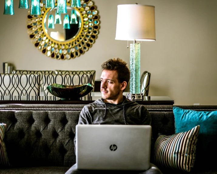 a man sits on the couch with a laptop