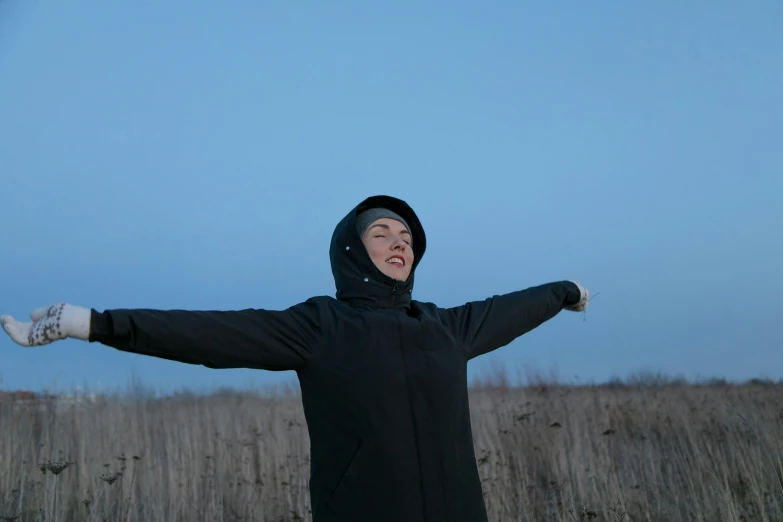 a woman in a black jacket with her arms outstretched