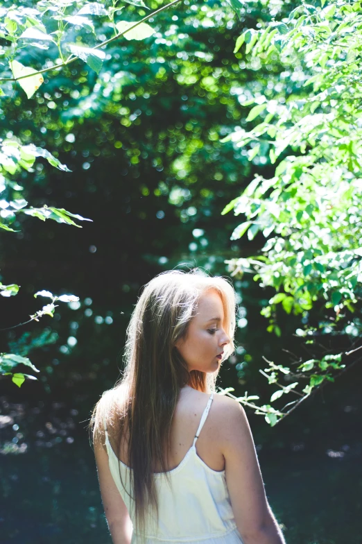 a young woman in front of some trees and bushes