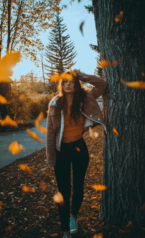 a woman standing against a tree with her head hanging out