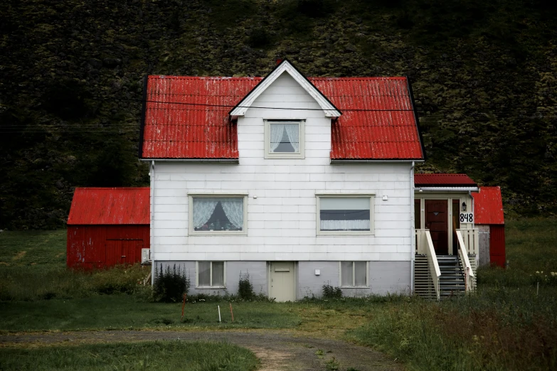 a red and white building sits in a grassy field next to mountains