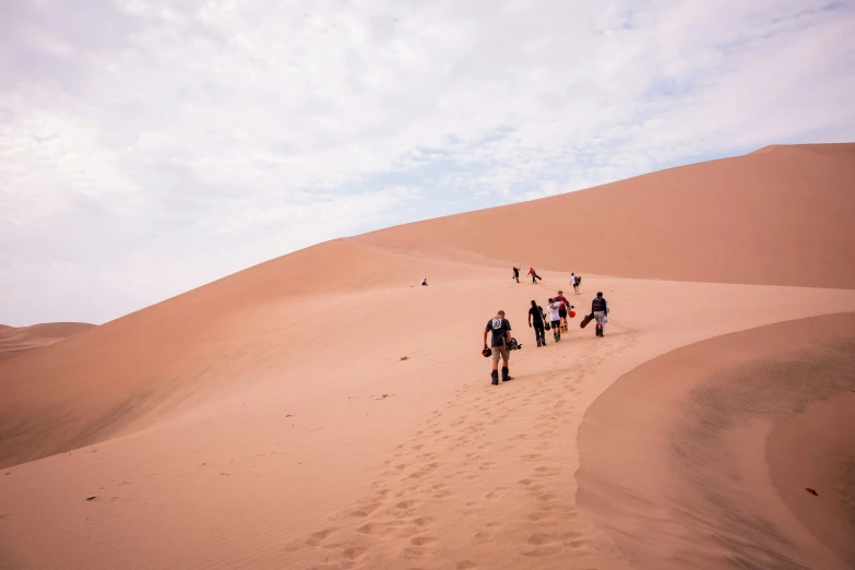 people walk down the sand of the desert