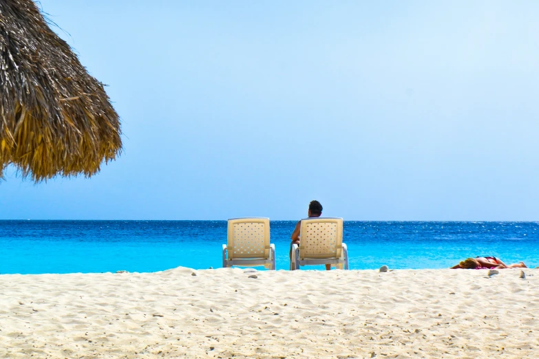 a couple sitting in chairs on top of a beach