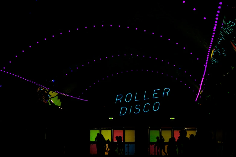 a building with a lighted roller disco sign at night