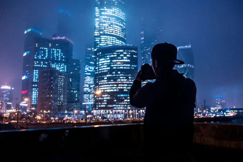 silhouette of a man taking a po in front of the skyline at night