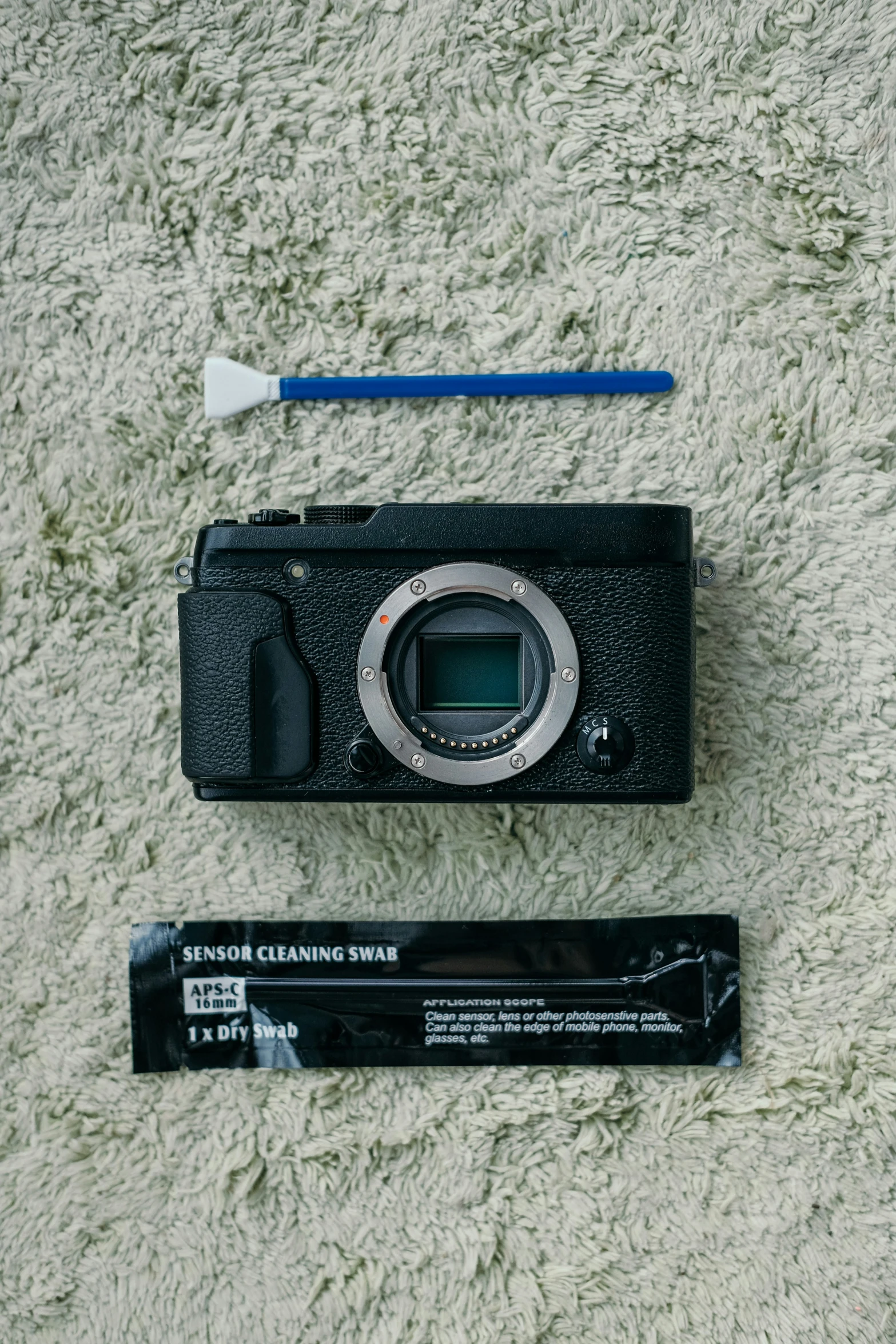 camera, battery and package lying on white carpet
