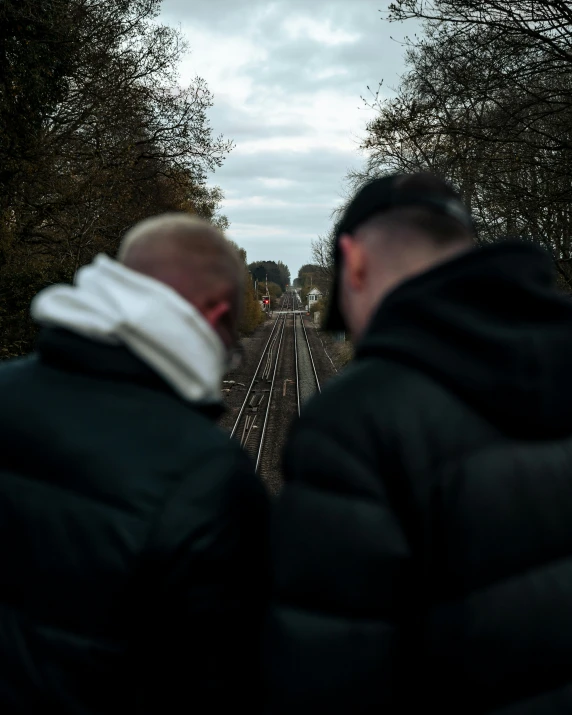 two people looking over a train track at another one