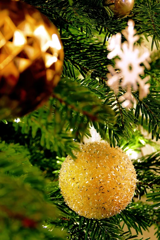 a yellow ornament hangs on the nches of a christmas tree