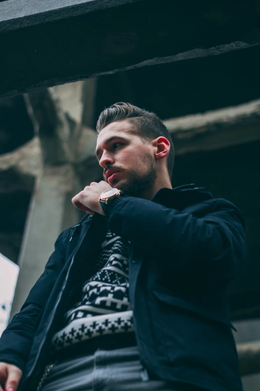 man in a black jacket is outside near an outdoor structure