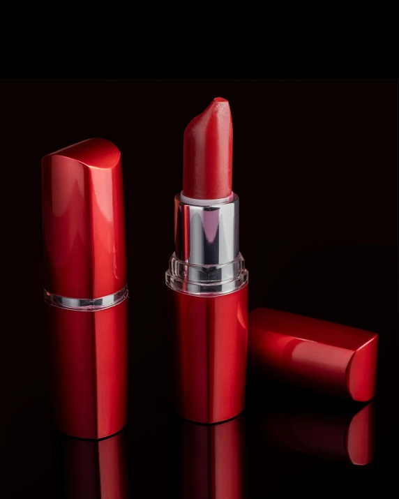 a red lipstick sits next to a silver container