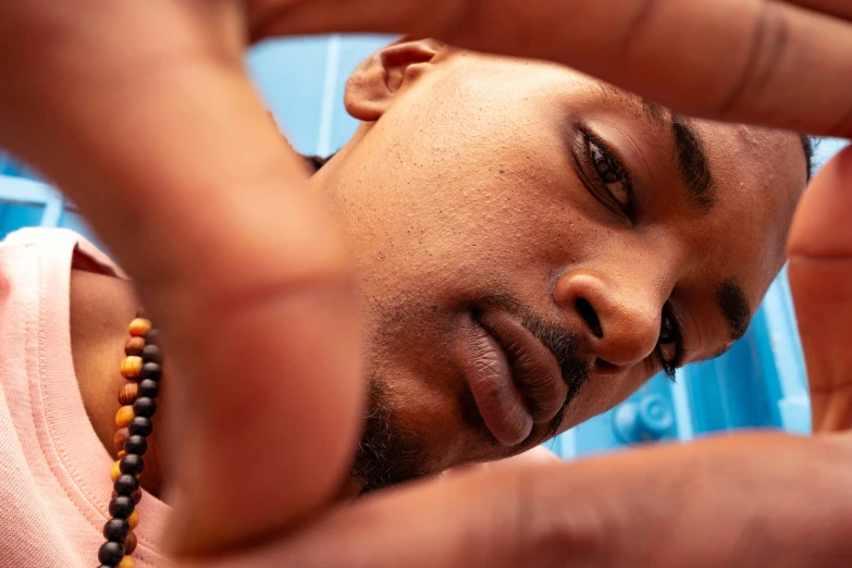 a young man adjusts his necklace on his neck