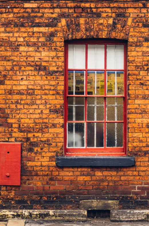 the side of a brick building has red window frames