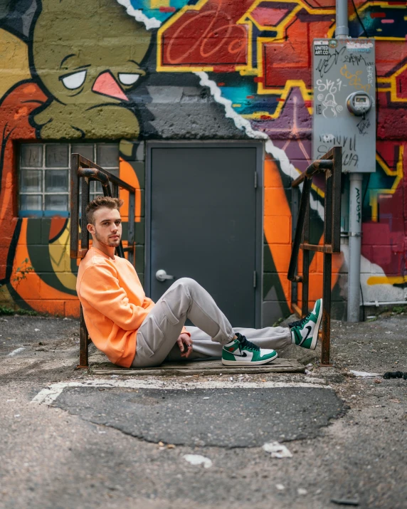 a man sitting on a chair in front of a wall with some grafitti on it