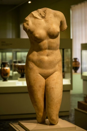 a statue of a woman, with hands in the air, inside a museum