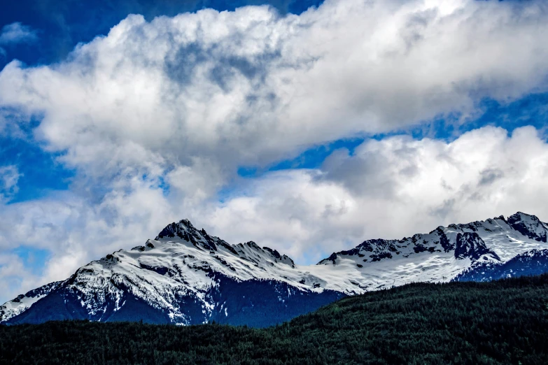 mountain range covered with snow under cloudy skies