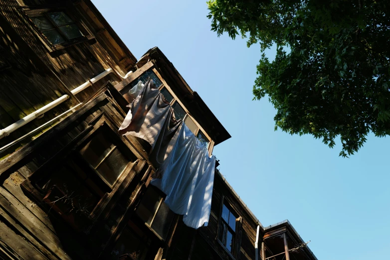 an old house in front of a tree with a washing line hanging on a line