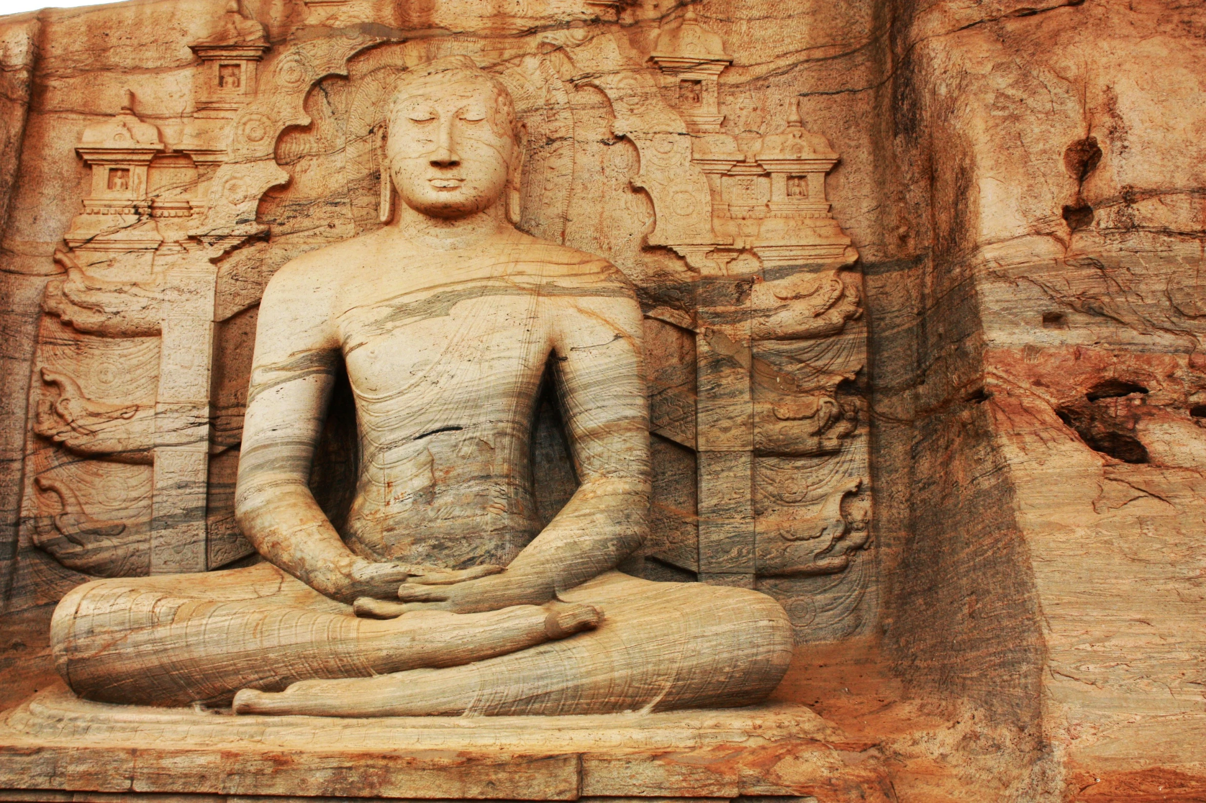 buddha statue seated in a small stone room