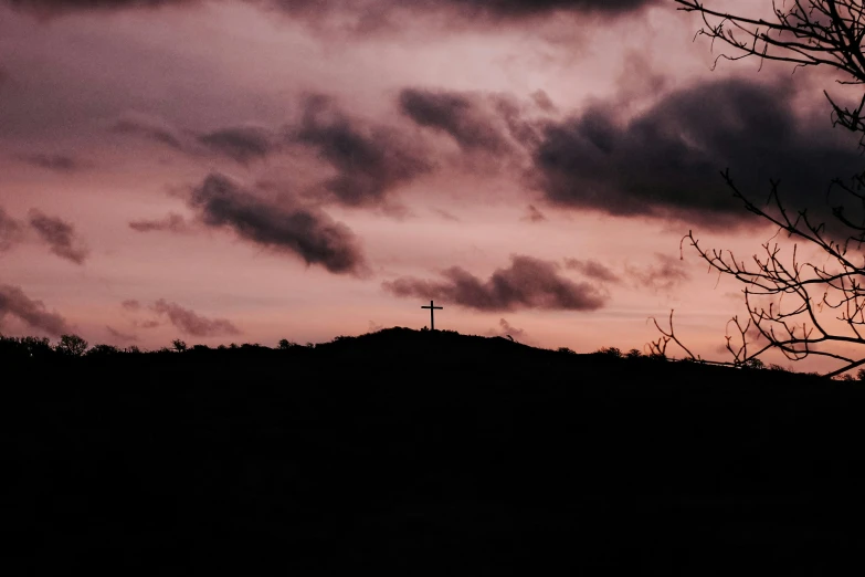 a sunset po looking at a cross atop the hill