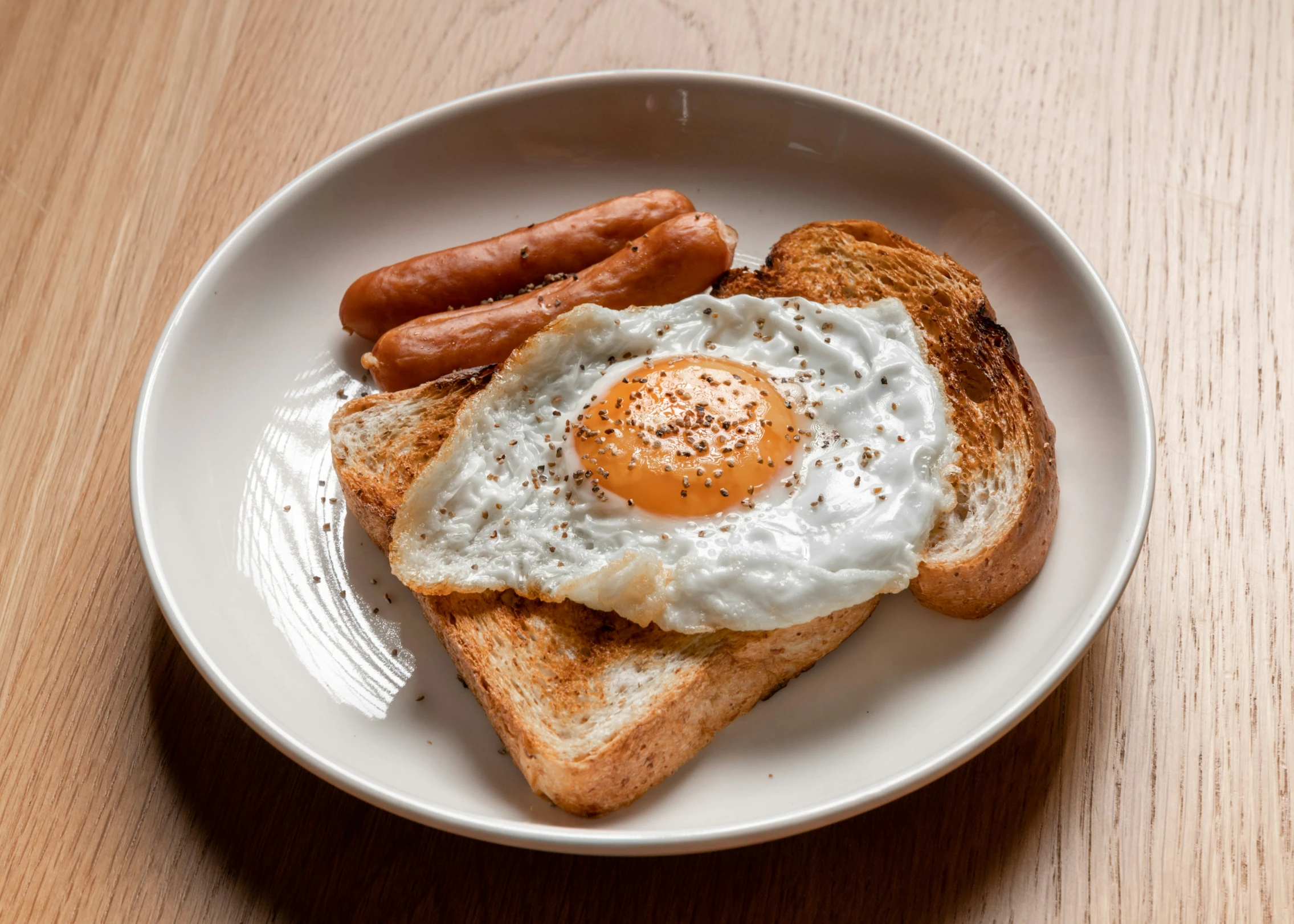 a plate of food containing bread, eggs and sausage