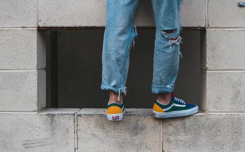 a person with yellow shoes standing against a cement wall