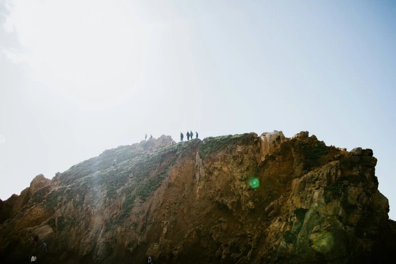 the people are walking on the rocks near the water