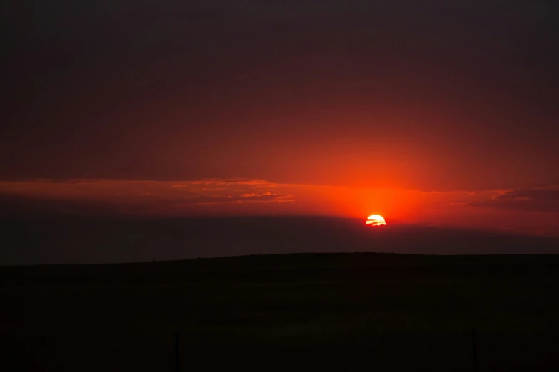 the sun rising over a mountain side with clouds and a sunset