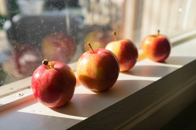 apples are placed on the windowsill near a window