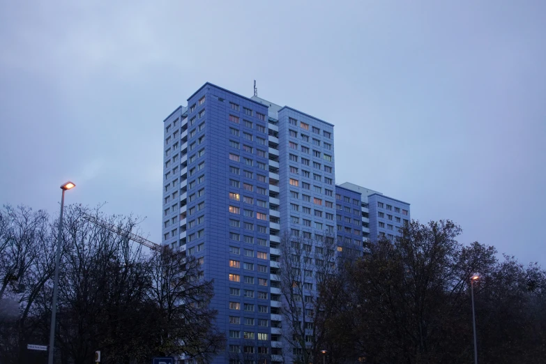 a tall building sits in the evening sky near some trees