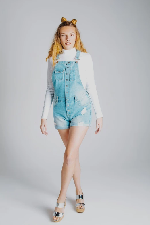 a girl in overalls and heels posing for a picture