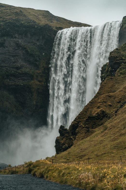 a waterfall on the side of a mountain near grass