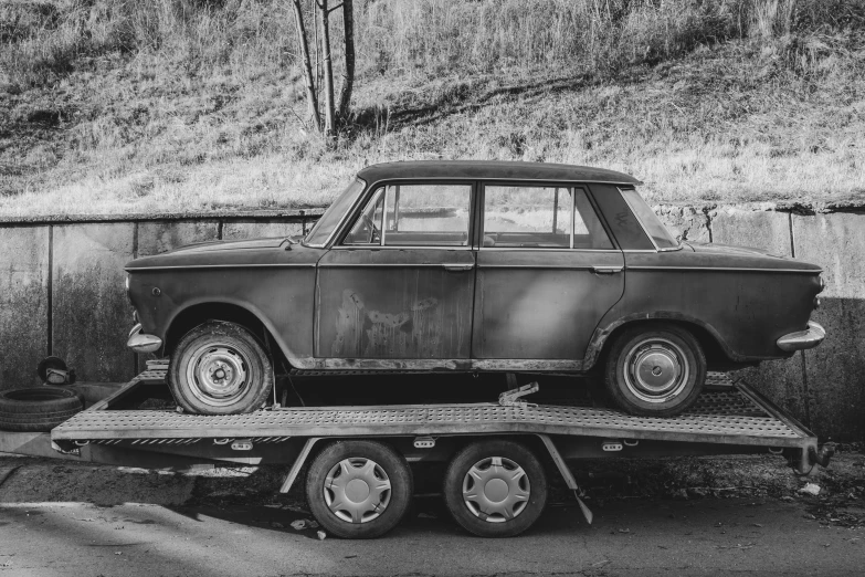 an old car is on the back of a flatbed tow truck