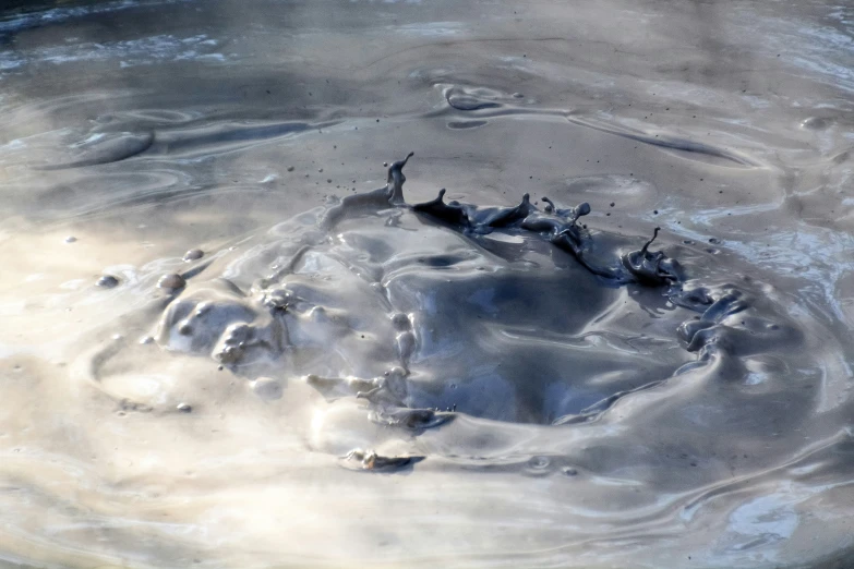 the ocean water has a rock and bubbles in it