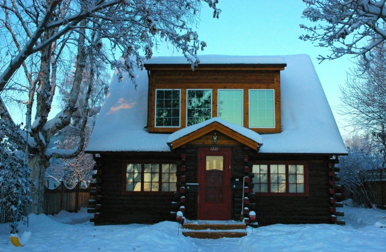 a log cabin sits in the deep snow