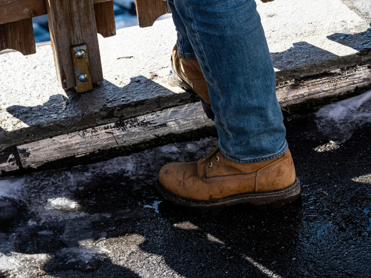 a man's leg wearing jeans and boots standing in the rain