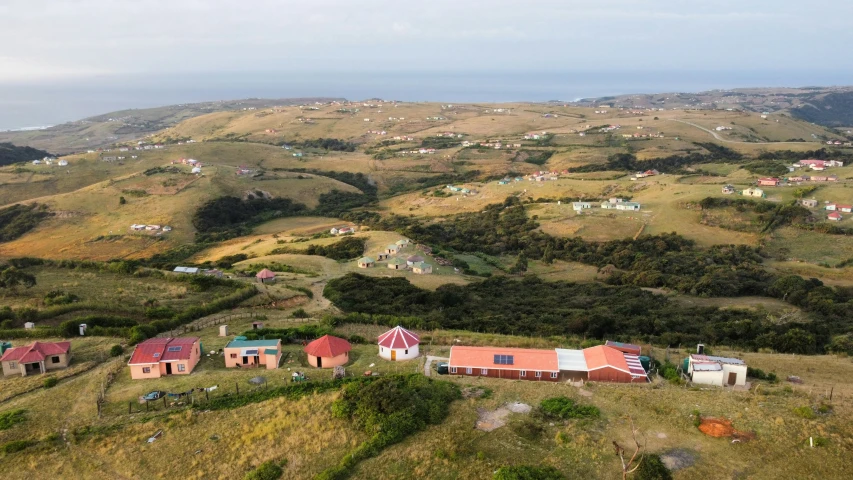 a small farm on a hill overlooking mountains