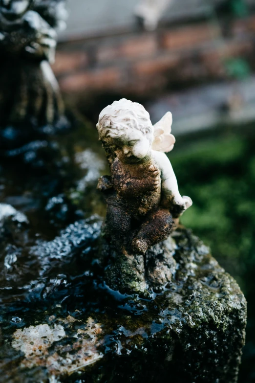 a small angel figurine on a rock with moss