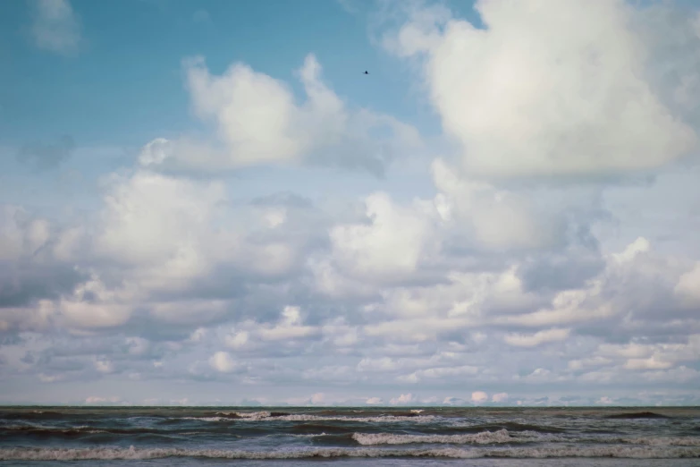 waves crashing on a sandy beach with blue sky in background