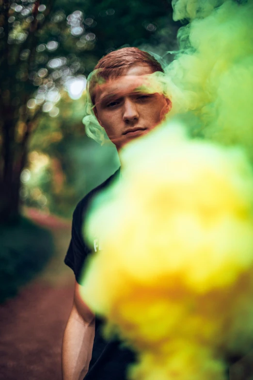 a man looks at the camera and holds onto a green smoke bomb