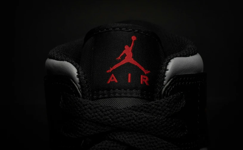 black and red air jordan logo on top of a pair of shoes