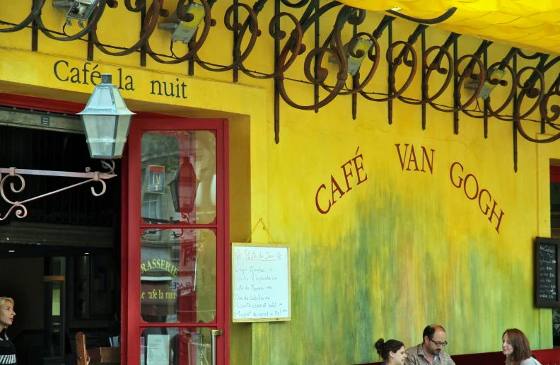 people sitting outside of cafe van gout near a light